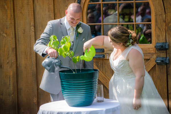 bride and groom watering their tree with elephant and dinosaur watering cans at fawn hollow acres