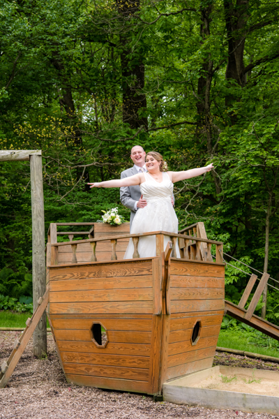 Bride and Groom doing a 'titanic pose' on the Pirate ship playground at Fawn Hollow Acres