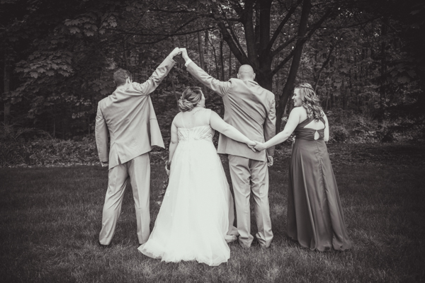 black and white photo of best man fist bump with groom and maid of honor/sister and bride holding hands at fawn hollow acres