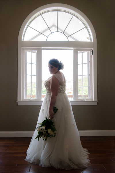 huge decorative front window at Fawn Hollow Acres with bride standing in front of it looking down and to the side
