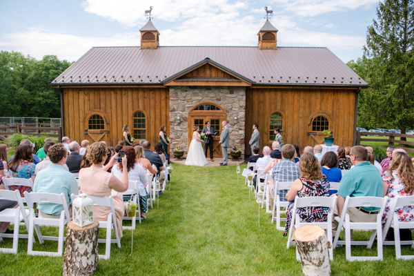 Wedding ceremony in front of rustic and stone barn at Fawn Hollow Acres