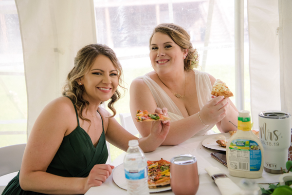 Bride and Bridesmaid enjoying Nooner's pizza truck pizzas at fawn hollow acres