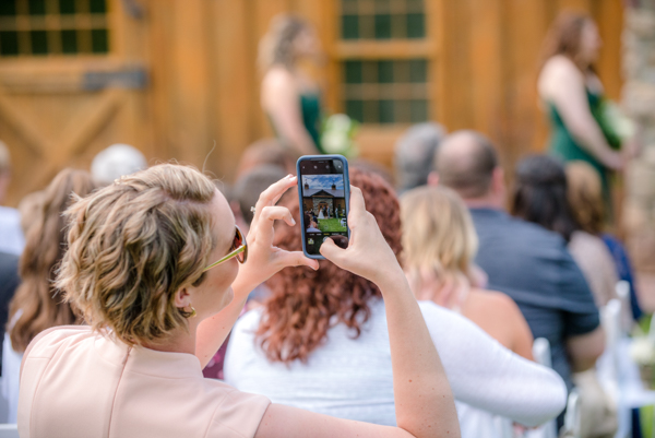 a lady taking a picture with her cell phone during the ceremony and only the cellphone screen is in focus at fawn hollow acres