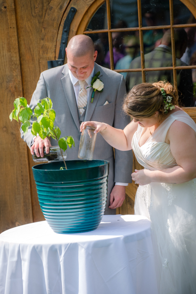 bride and groom putting dirt from their childhood homes in a potted tree at fawn hollow acres