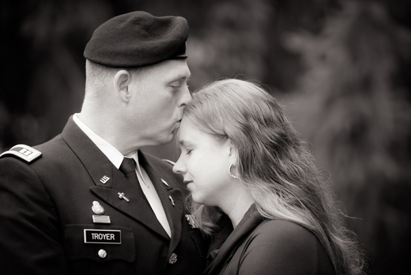 Black and white photo of an Army Chaplain kissing his wife on the forehead
