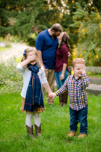 J and D studio family photo of parents blurry in background kissing and kids holding their hands over their eyes in front, Harrisburg, PA