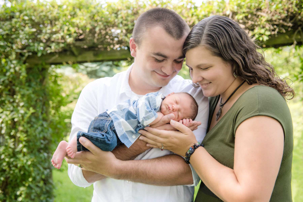 J and D studio newborn family photo outdoor with flower hedge behind them blurry, Harrisburg, PA