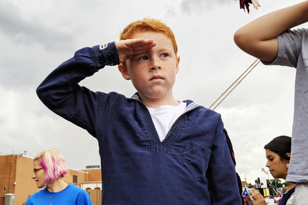 Boy in Navy uniform saluting the American flag