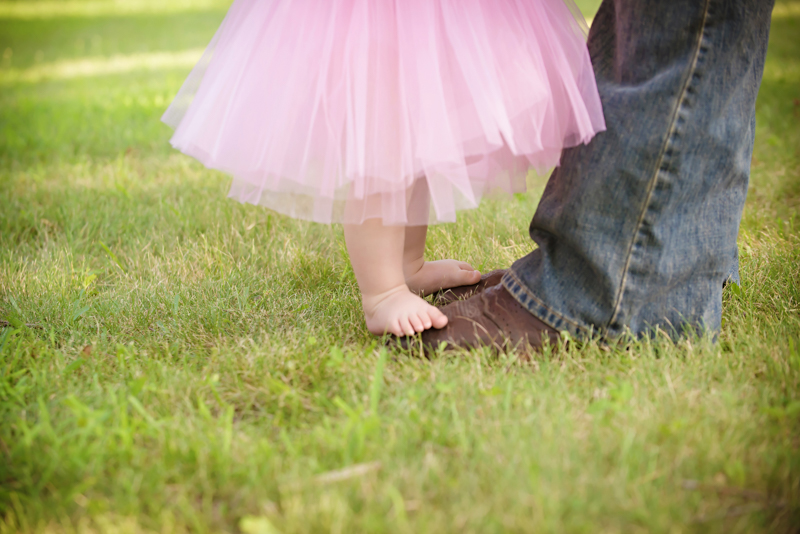 daddy in cowboy boots and jeans with little girl feet on top of his boots. close up with tutu on baby girl