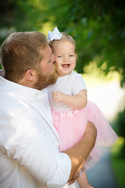 daddy holding baby girl in tutu, kissing her on the cheek