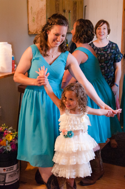 Bridesmaid in aqua playing with the cute little curly haired flower girl while bridesmaids and "I DO" Details coordinator laugh together in the background.
