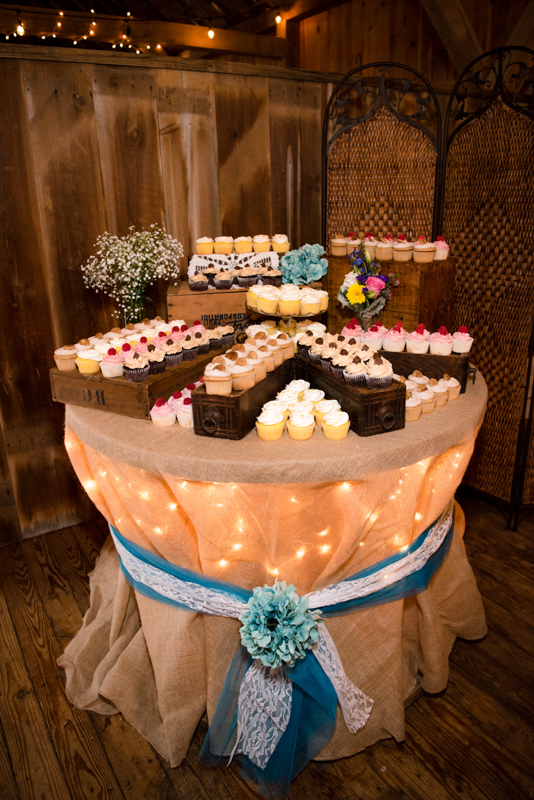 Cupcake stand set up on a burlap tablecloth with ribbon around it and lights behind it.  Taken by J & D Studio, Harrisburg Photographers